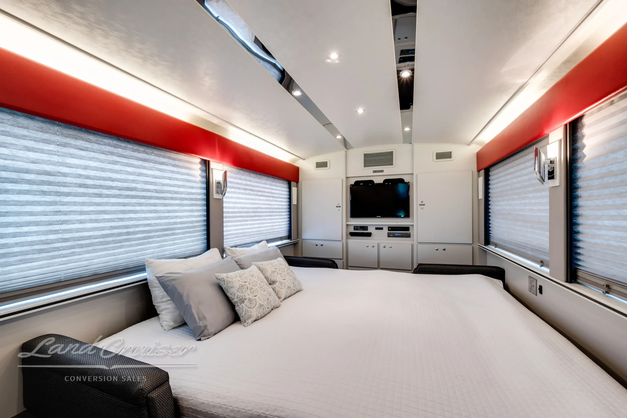 Rear sleeping area in MCI Executive Day Coach with wide bed, accent lighting, and panoramic side windows