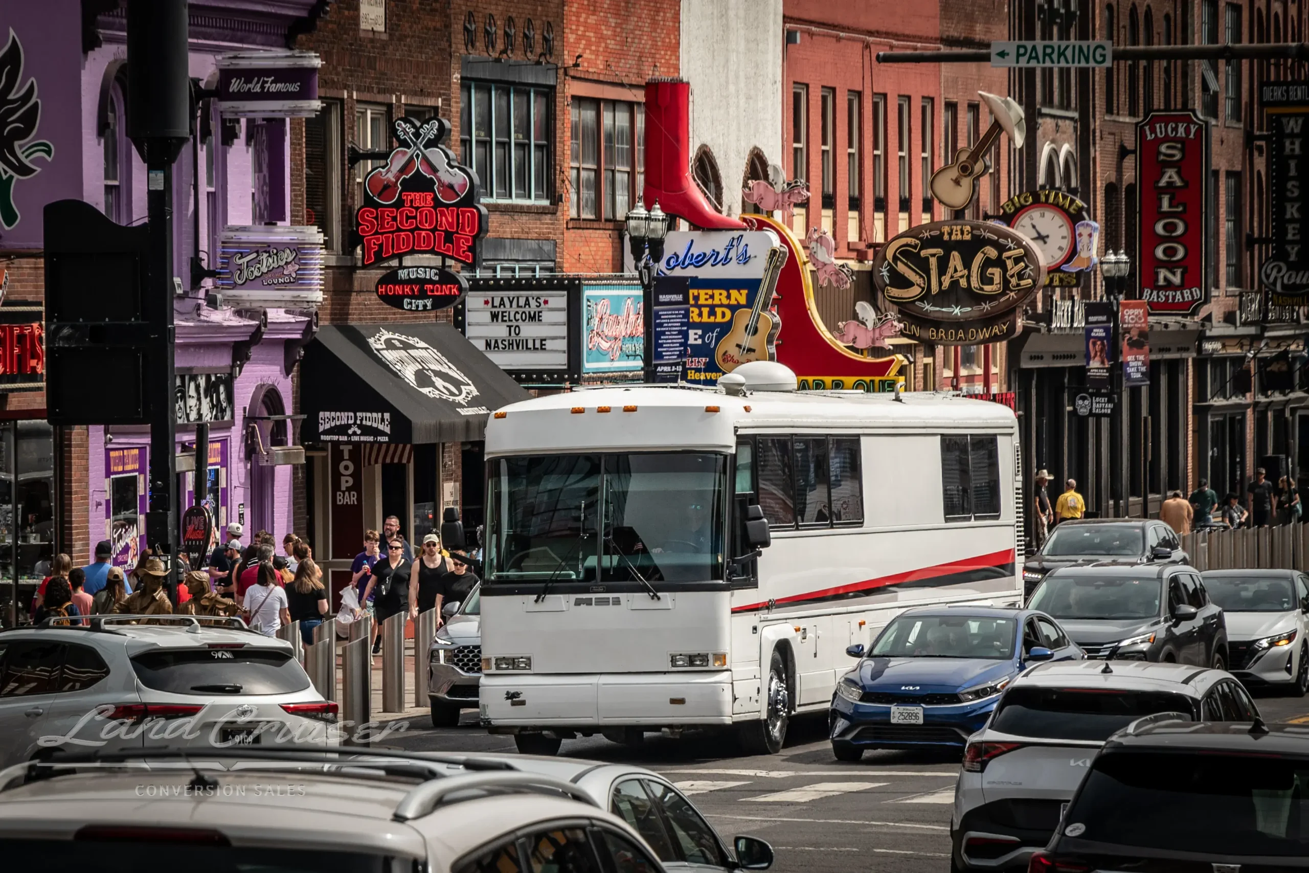 MCI 102-DL3 Executive Day Coach driving through Broadway in downtown Nashville with crowds and neon signage