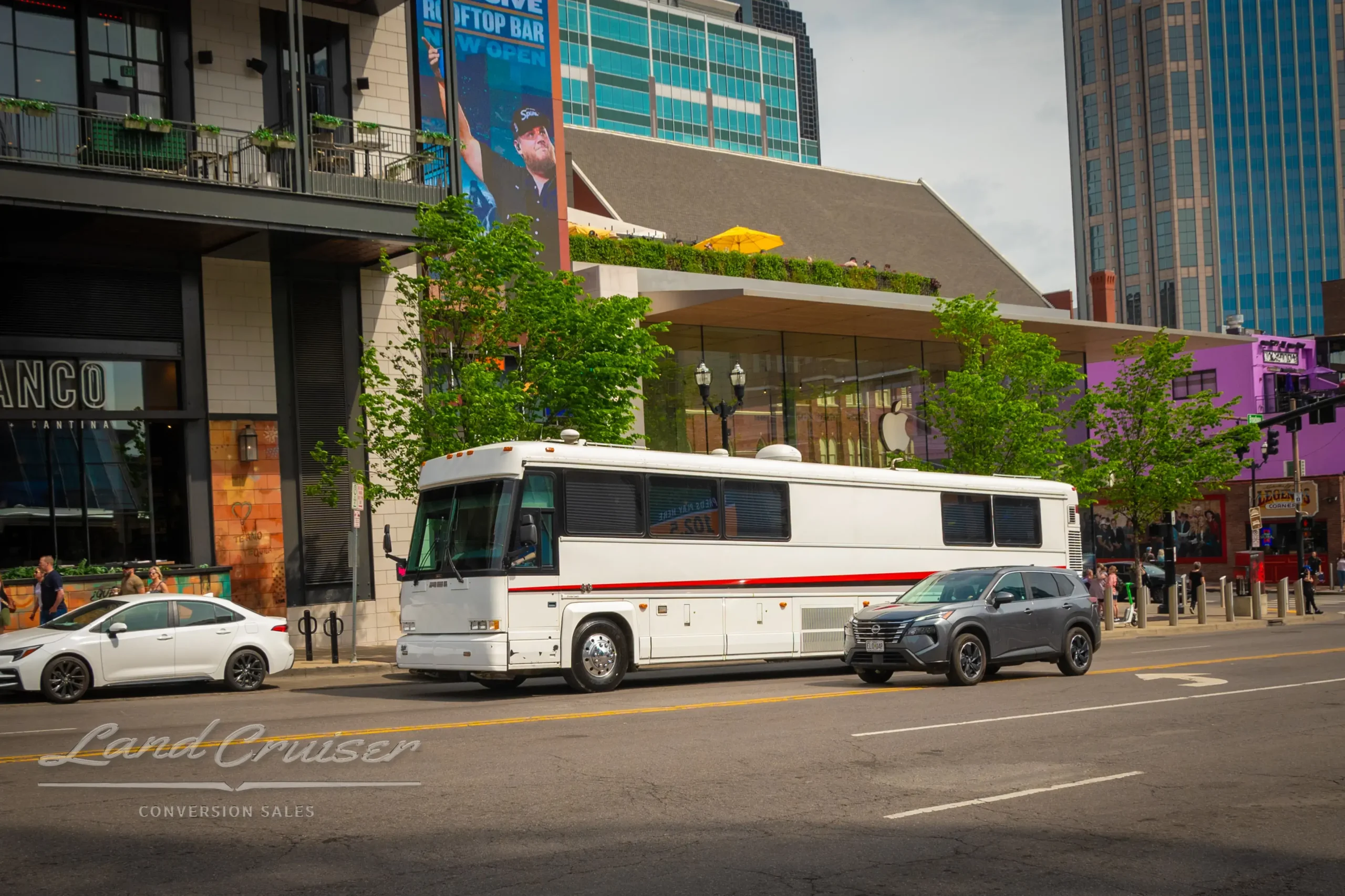 Side profile of MCI 102-DL3 parked along downtown Nashville’s Fifth + Broadway complex