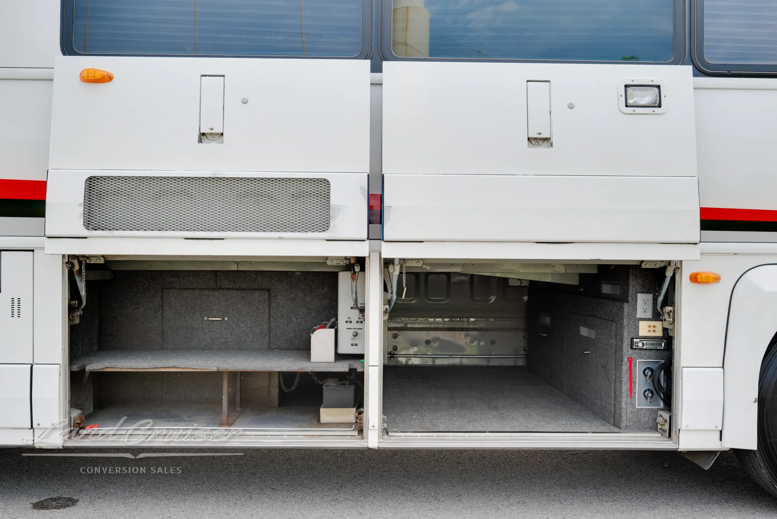 Open underbay compartment in MCI bus showing carpeted storage space and utility access