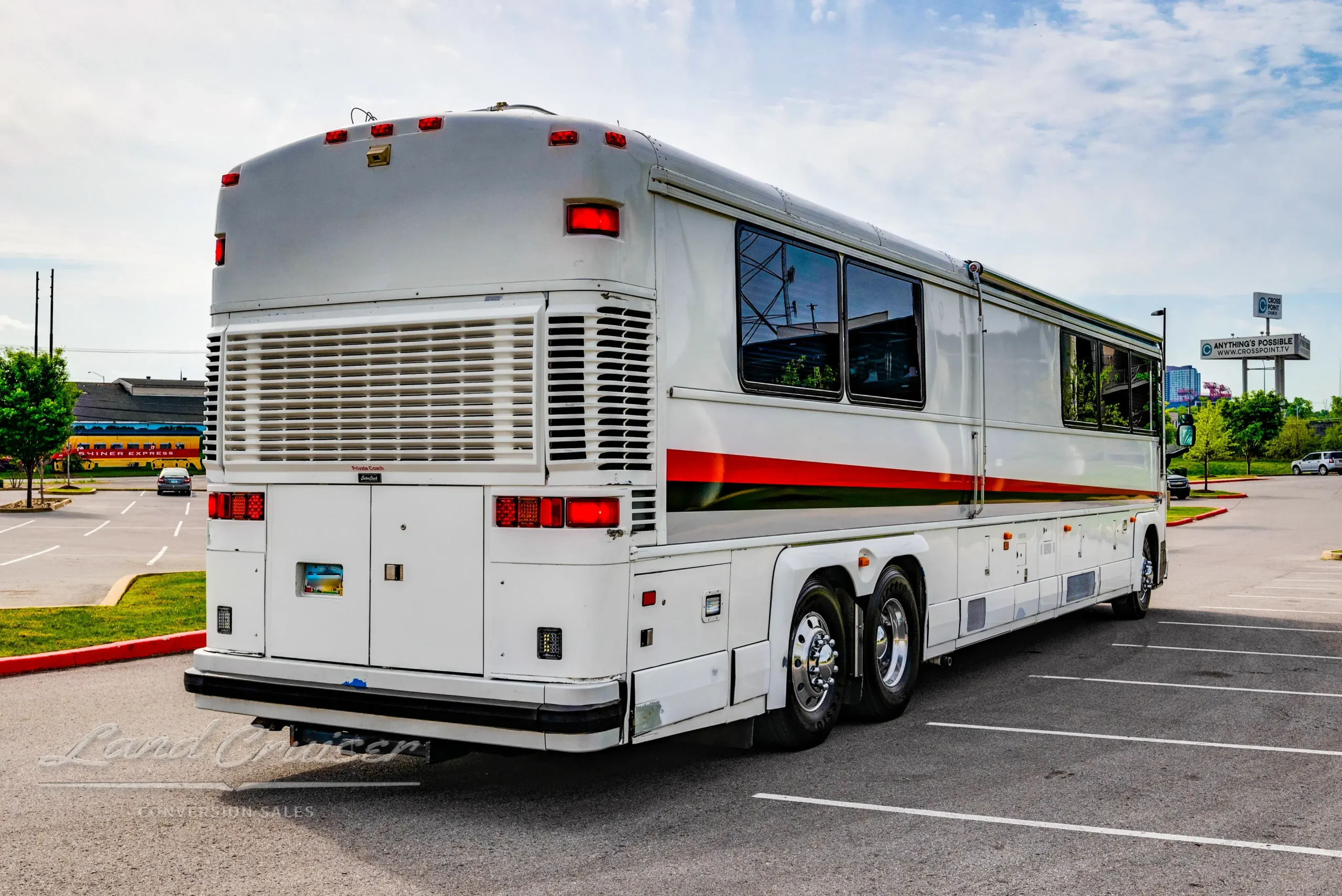 MCI 102-DL3 shown from rear angle with curved corner, dual rear axles, and clean white exterior