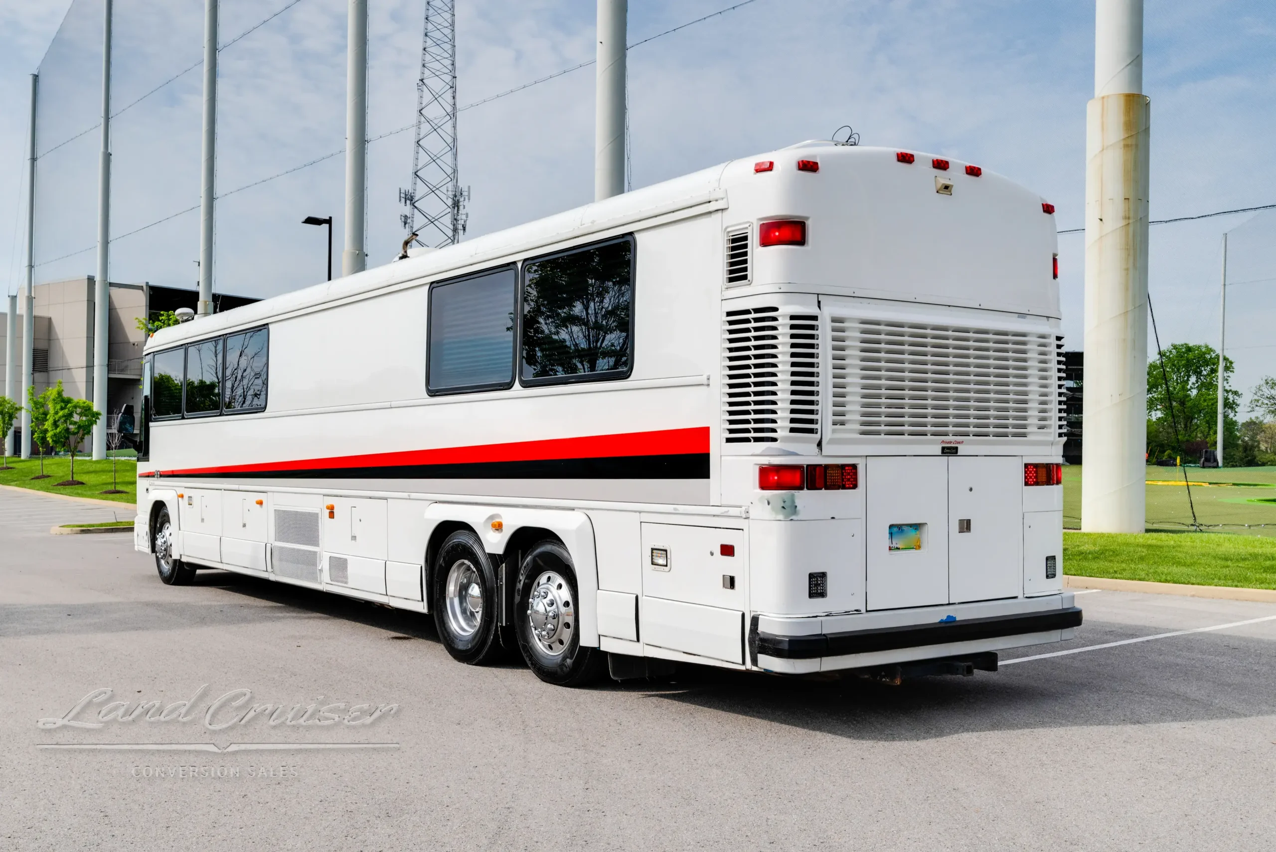 Wide shot of MCI Executive Coach from driver’s rear angle with polished wheels and vent panels