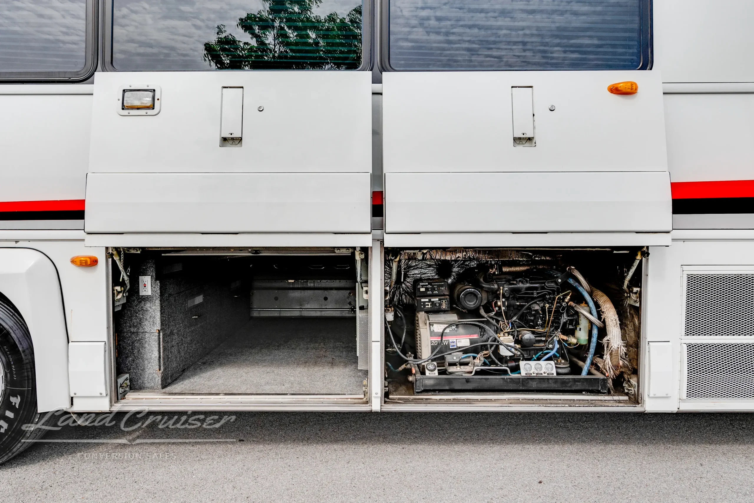Open side bay showing coiled hoses, water pump system, and wiring access panel