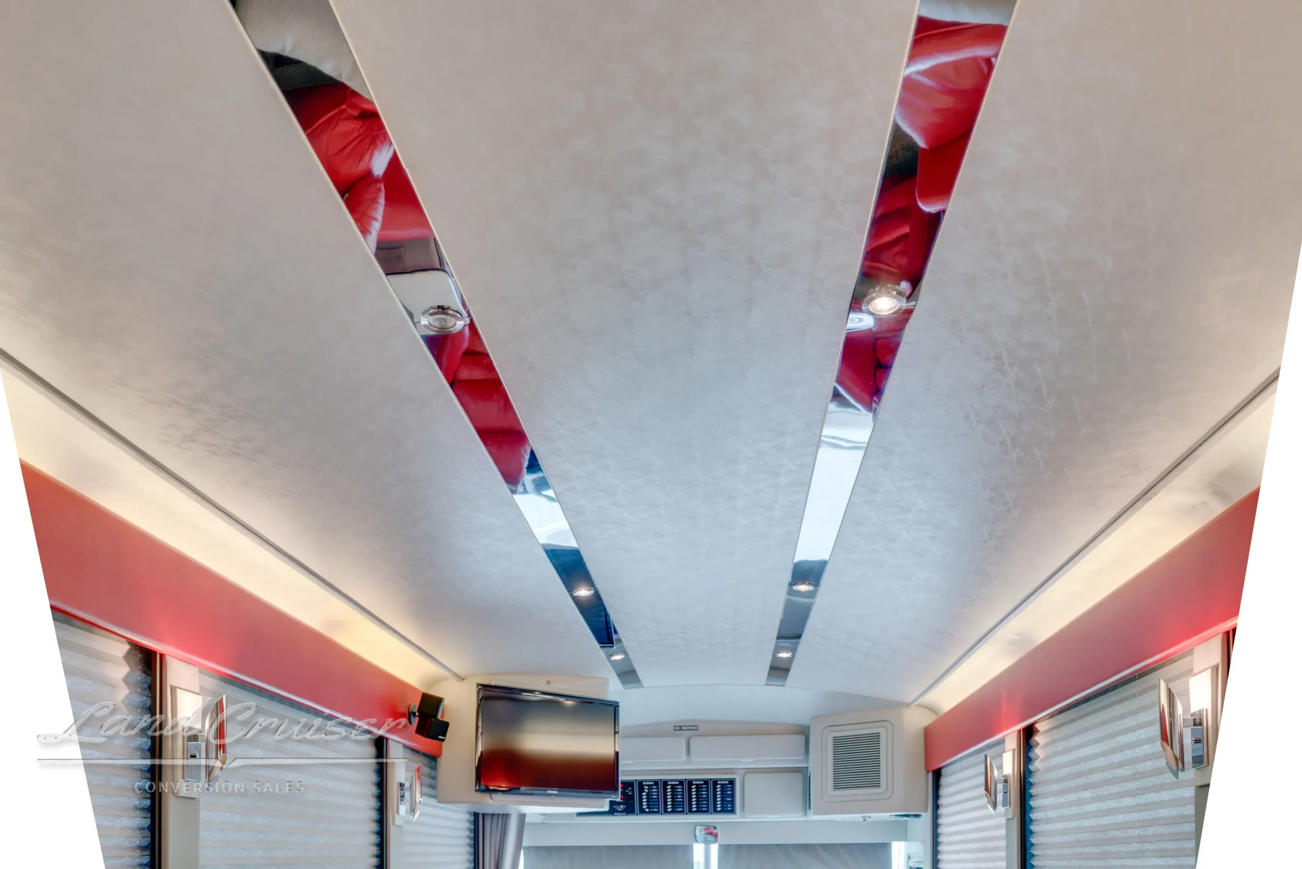 Red-accented ceiling design inside MCI coach with integrated lighting and mirrored panels