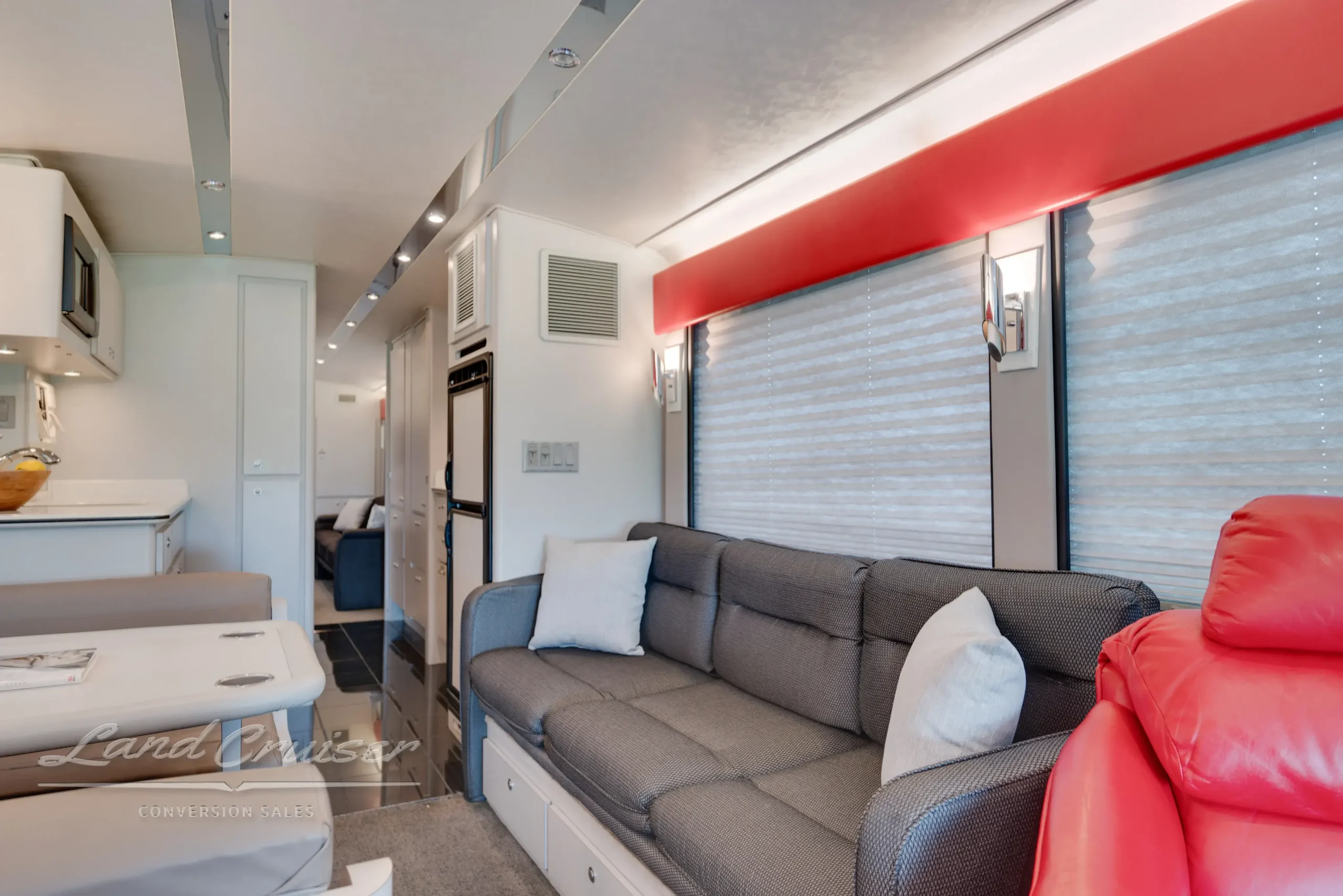 Galley kitchen in MCI bus featuring fruit basket display, white cabinetry, and solid surface countertops
