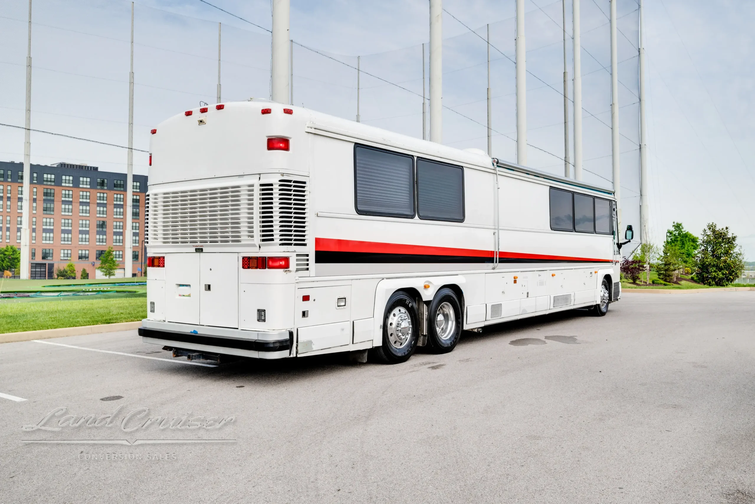Driver-side rear quarter view of 1998 MCI 102-DL3 parked in open lot with polished trim and full skirting