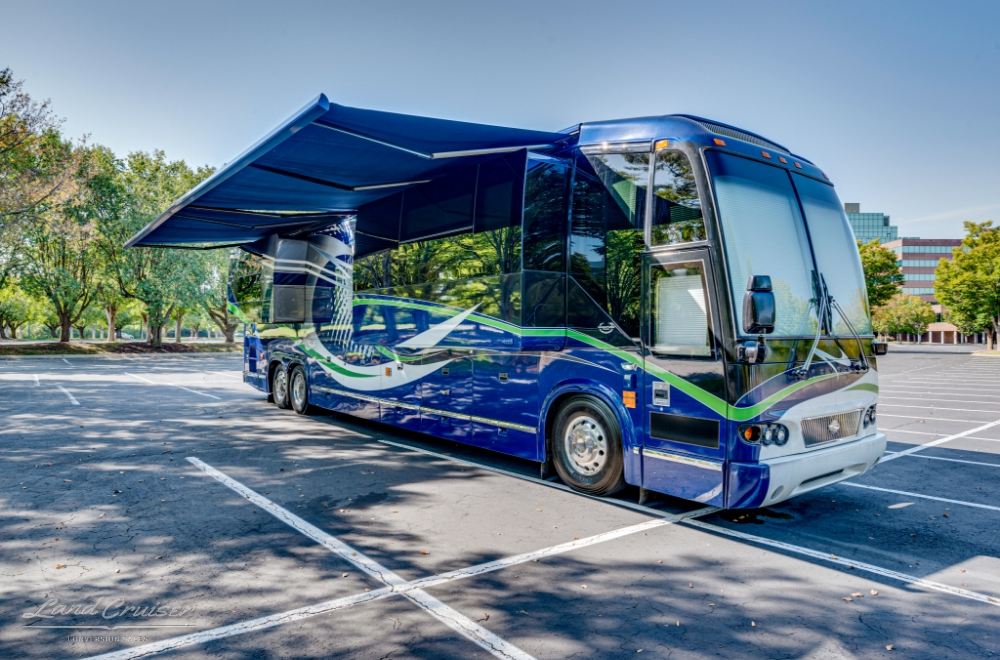 Awning extended on the passenger side of a prevost bus parked in a parking lot.