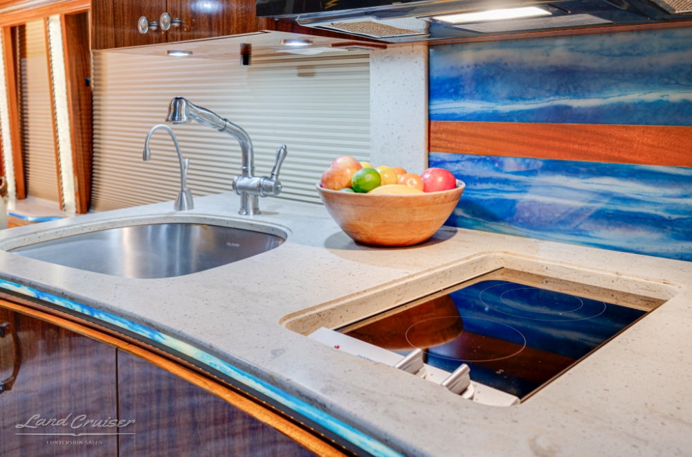 close up view of kitchenette with stovetop and sink along with backsplash details.