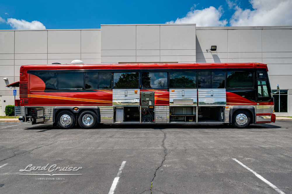 Full side view of Custom Coach 4510 with all storage and service bays open in parking lot