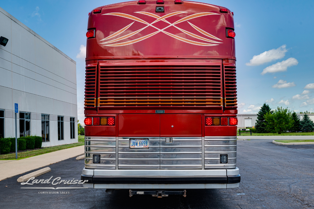 Rear view of 2001 MCI 102DL3 executive bus with custom red graphics and roof access ladder