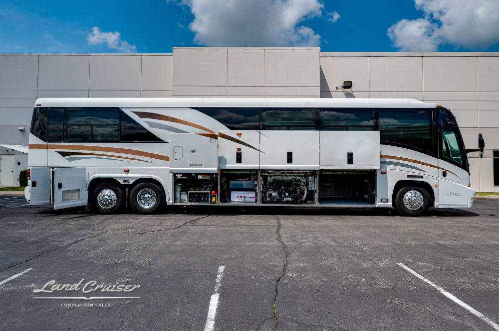 Full driver-side profile of MCI 102EL3 motorhome “Sunset” parked in open lot