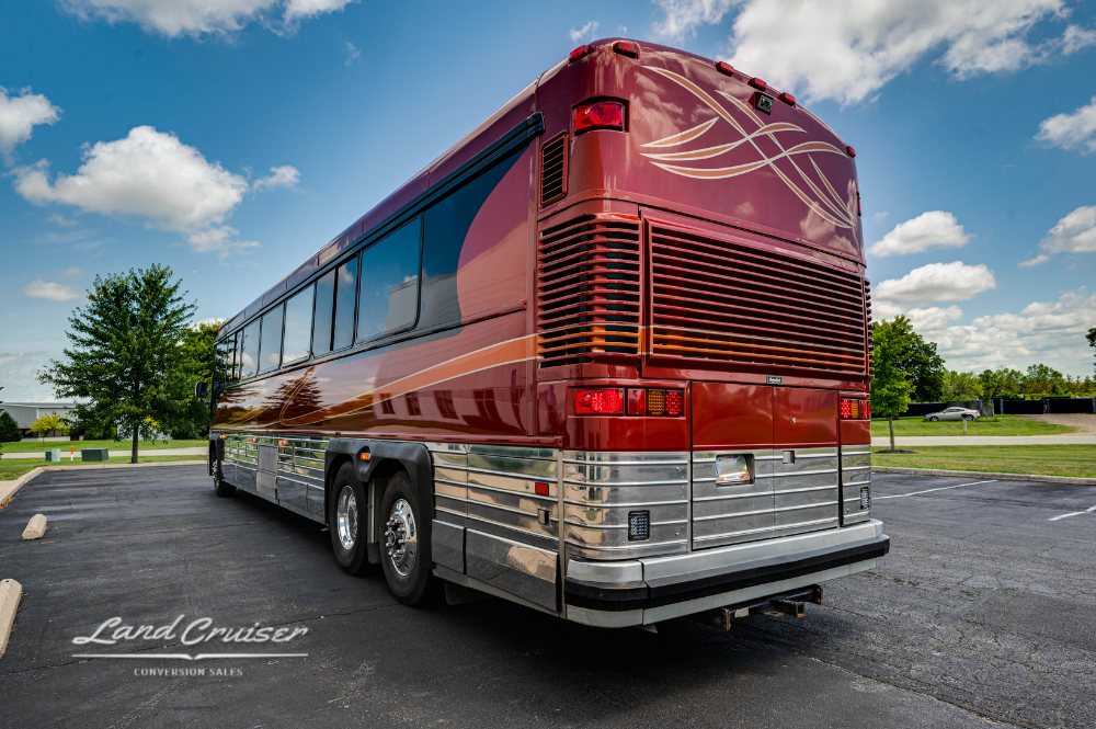 Rear driver-side angle of Churchill executive coach showing triple axles and clean exterior lines