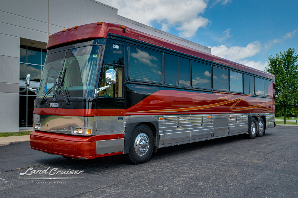 Front angle of 2001 MCI 102DL3 Executive Coach by Custom Coach with red and silver paint parked outside building
