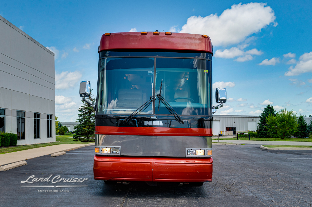 Front view of red and silver 2001 MCI executive coach with wide windshield and dual mirrors