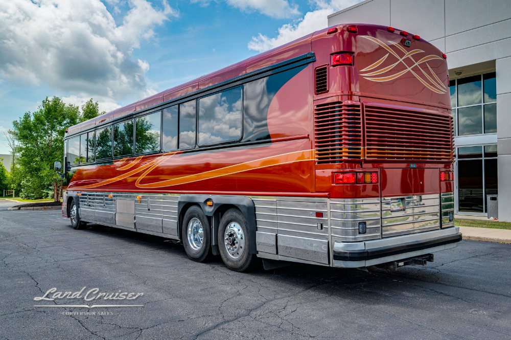 Rear passenger-side angle of Custom Coach 4510 showcasing aerodynamic rear cap and bold paint scheme