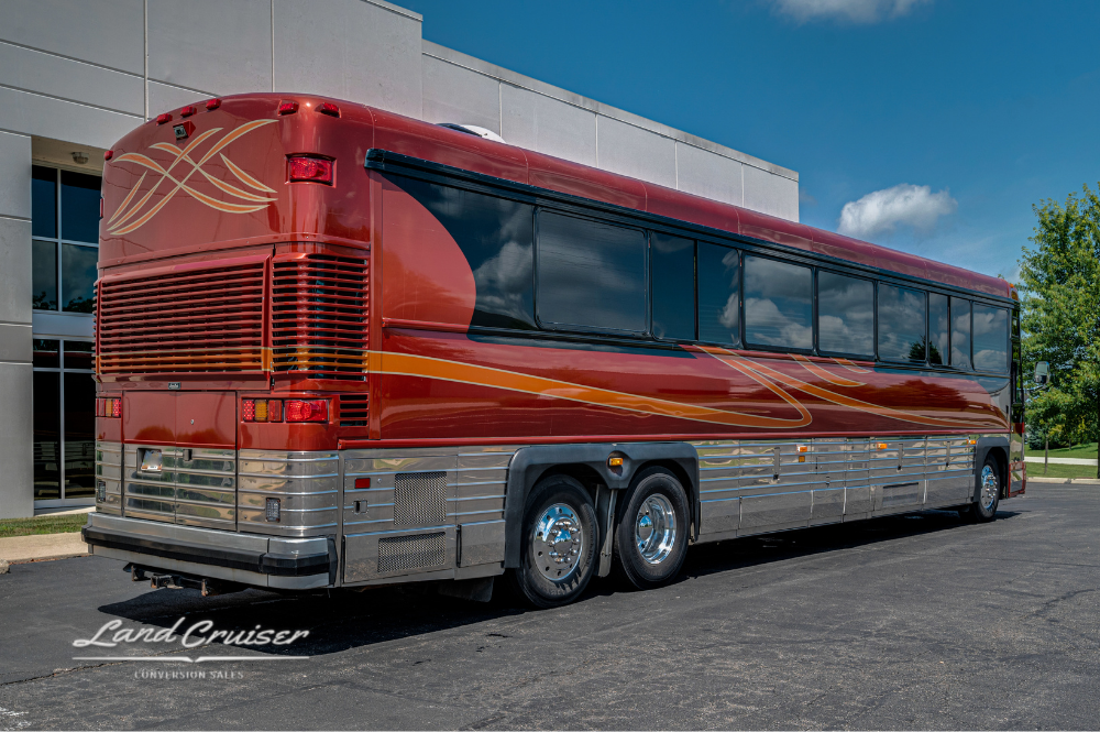 Rear angle of MCI 102DL3 executive coach featuring polished stainless siding and rooftop A/C vents