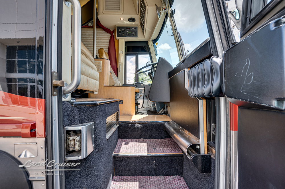 Entry stairs and front lounge view of 2001 MCI executive coach with beige leather seating