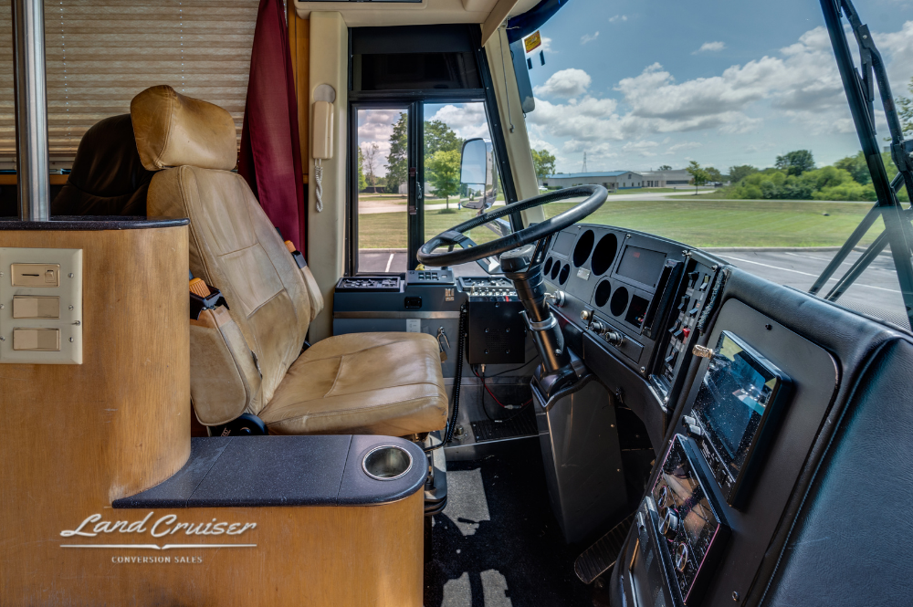 Driver’s cockpit with tan leather captain’s chair and full dashboard of Churchill executive coach