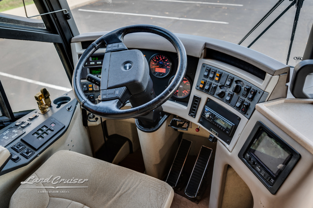 Driver’s cockpit of MCI 102EL3 motorhome with leather captain’s chair and full dashboard controls