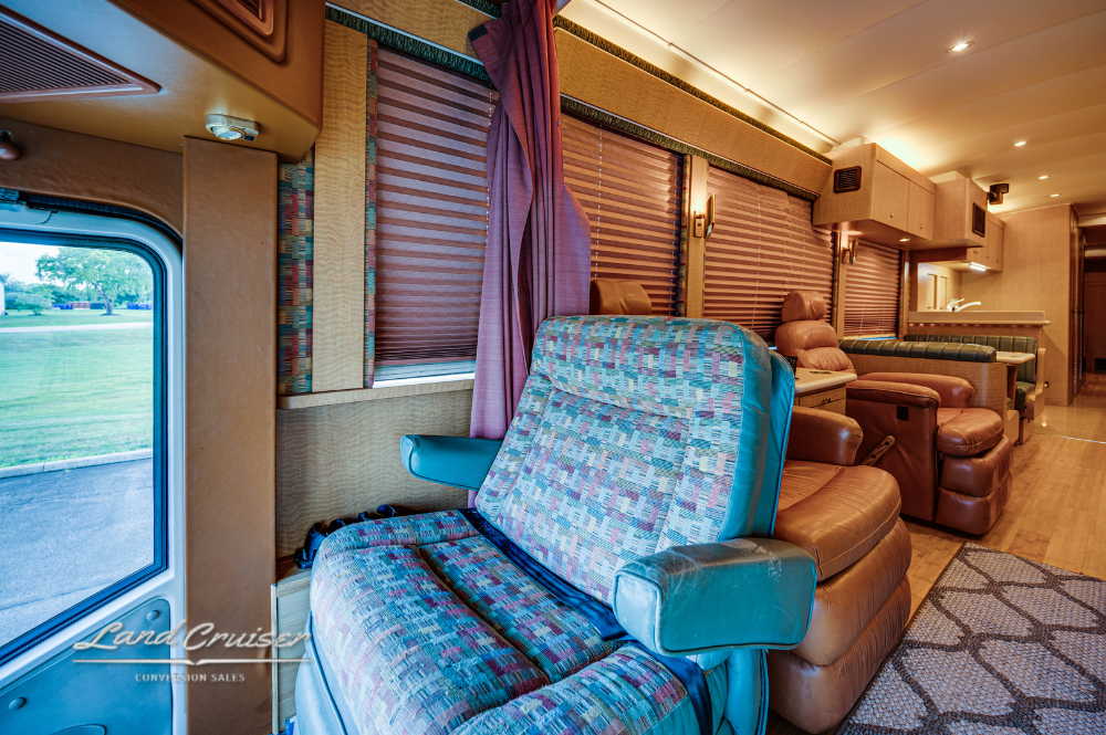 Side view of front lounge featuring blue leather sofas and day/night shades