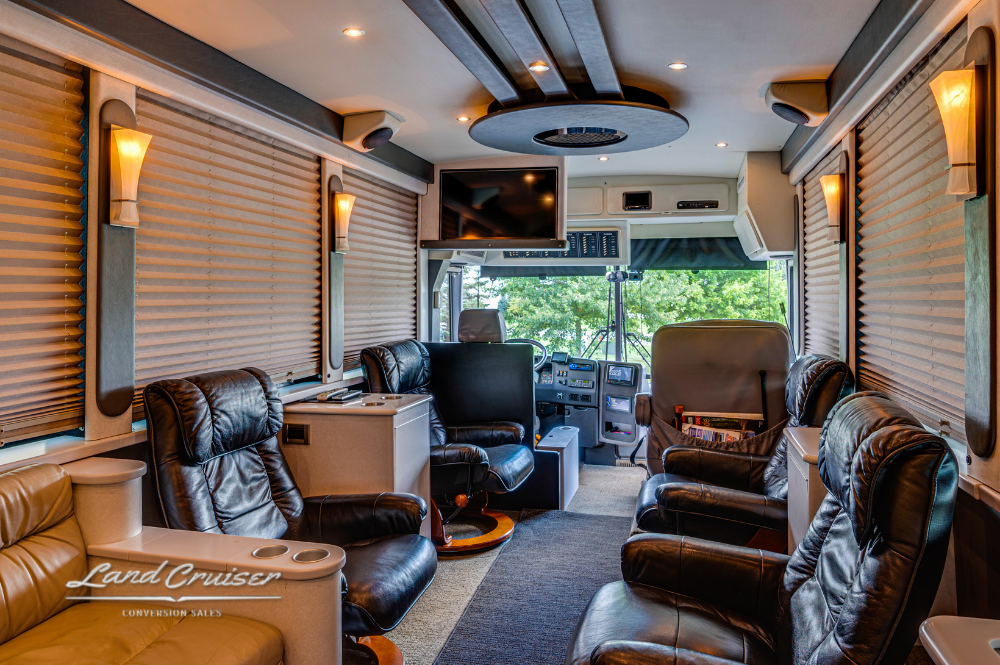 Wide-angle view of lounge with captain’s chairs, window shades, and overhead media console