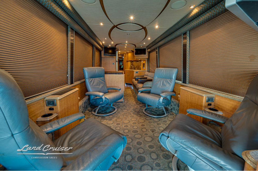Four leather captain chairs arranged in the main salon with overhead lighting and blinds drawn.