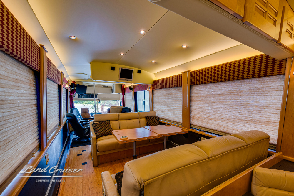 Rear lounge with leather couches and shades drawn for privacy, facing entertainment center