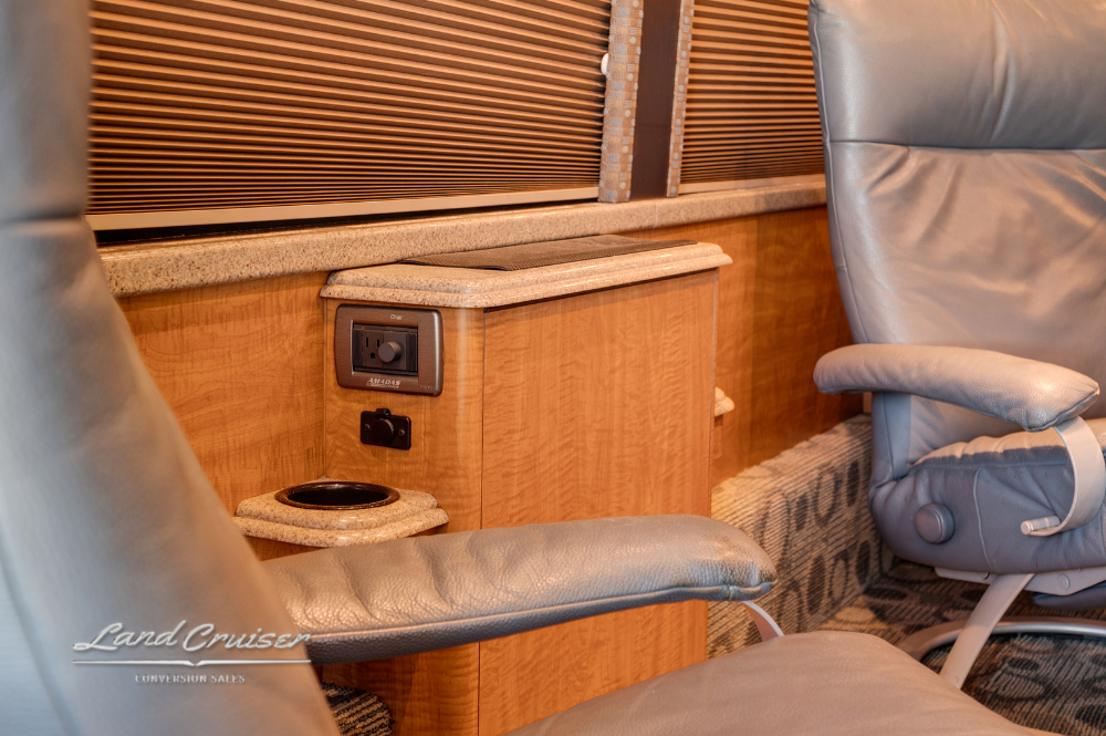 Close-up of reclining chair and console with built-in outlet and cup holder in salon.
