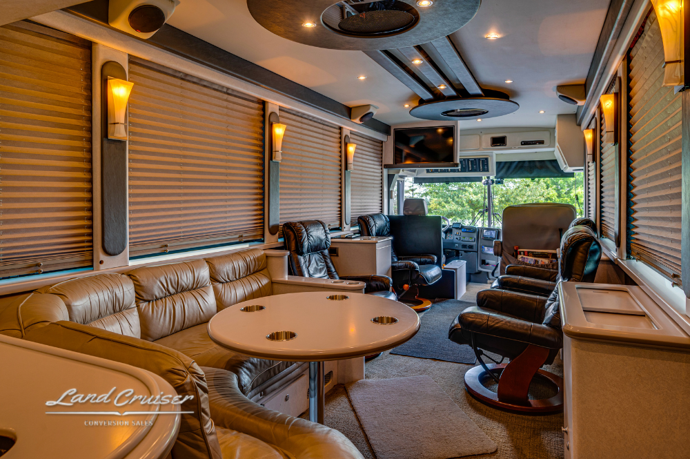 VIP lounge area featuring leather recliners, dinette table, and entertainment setup inside XLII coach
