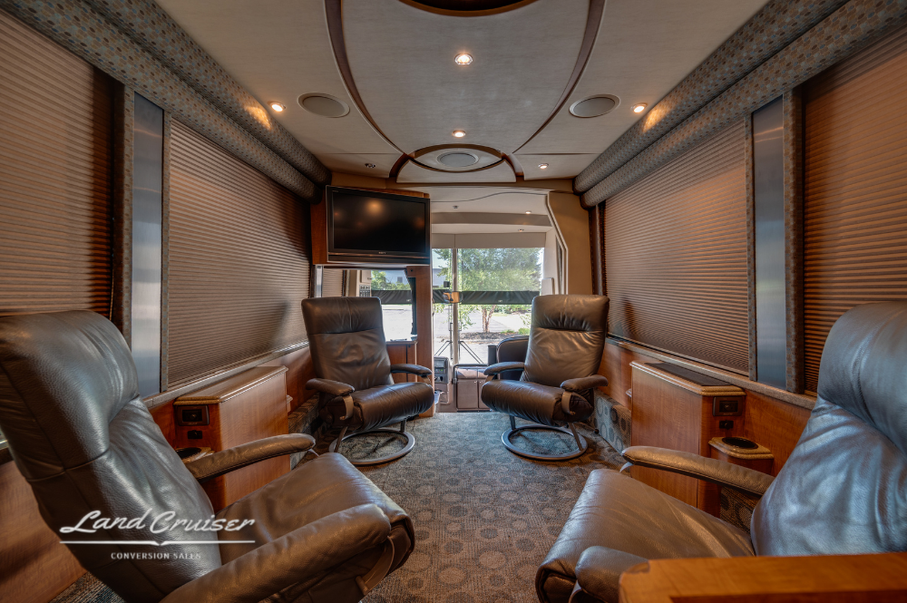 Front-facing salon view with captain chairs, flat screen TV, and entry door visible in the background.