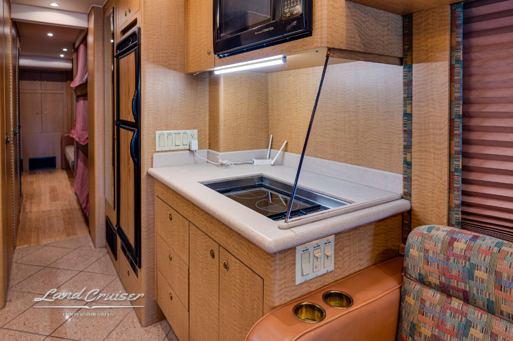 Galley with cooktop, solid surface counters, and storage cabinets in MCI motorhome