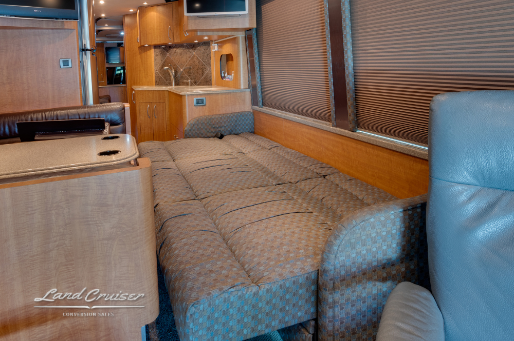 Folded-out sleeper sofa with view into galley and overhead storage compartments.