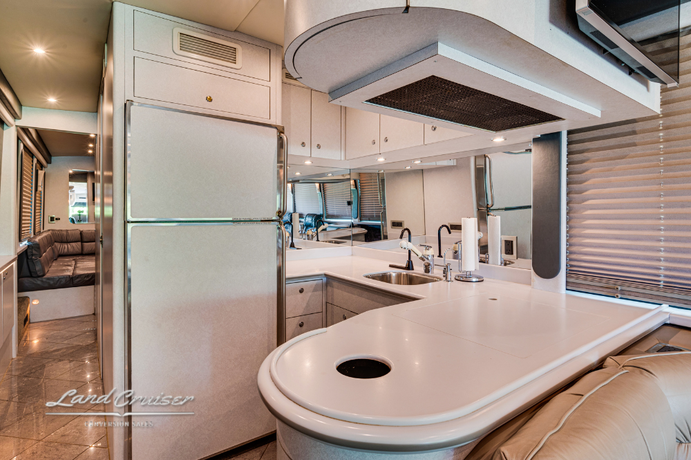 Wide view of galley kitchen with solid-surface counters and dinette booth in custom motorcoach