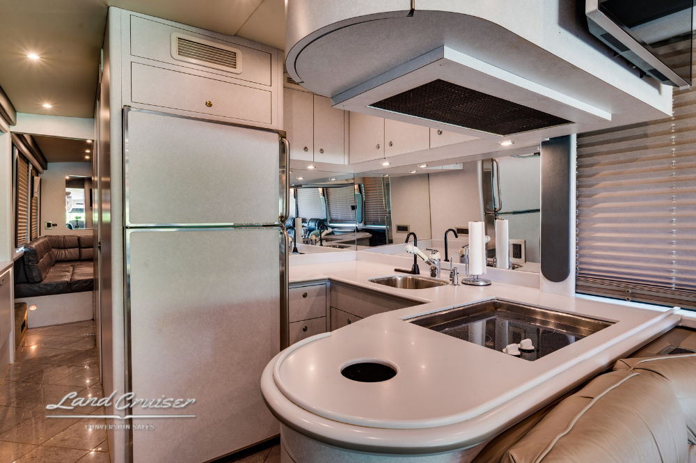 Open kitchen design with convection microwave, residential fridge, and dual sink in Prevost XLII