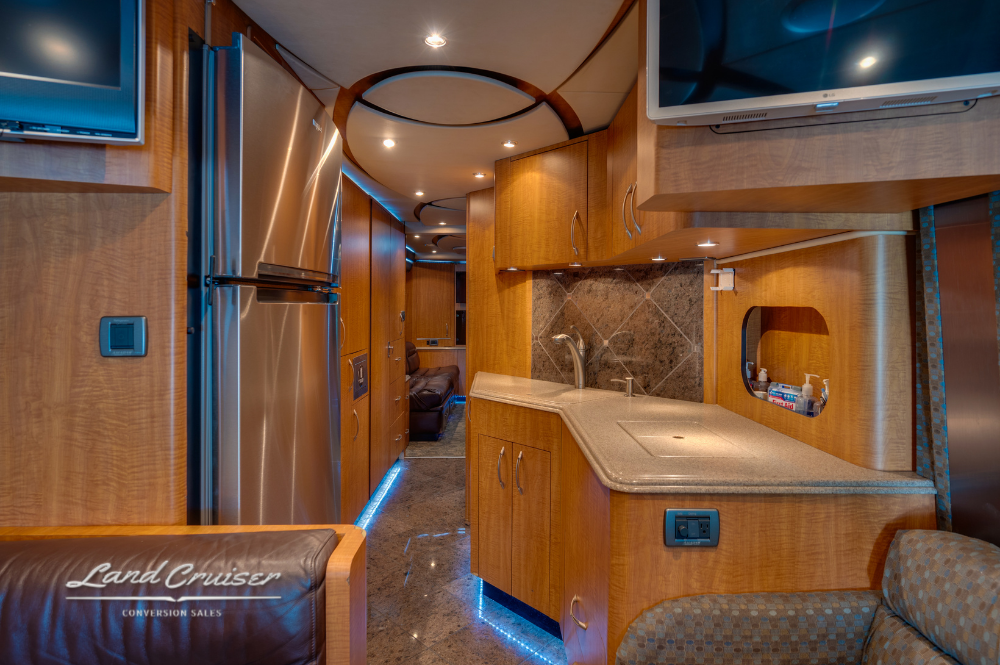Full kitchen and hallway layout with underlighting and stainless refrigerator.
