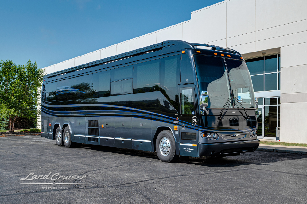 Front angle view of the 2008 Prevost H345 Executive Coach parked outside a commercial building, showcasing its sleek lines and dark reflective finish.