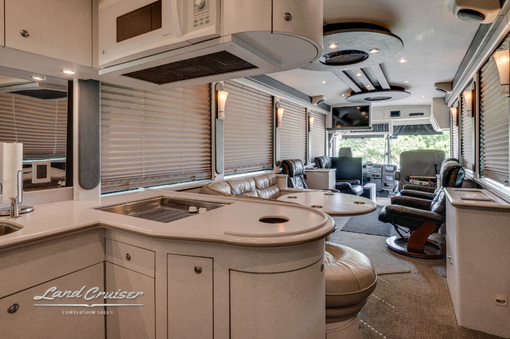 Complete kitchen view in luxury coach with curved countertops, custom cabinets, and open layout