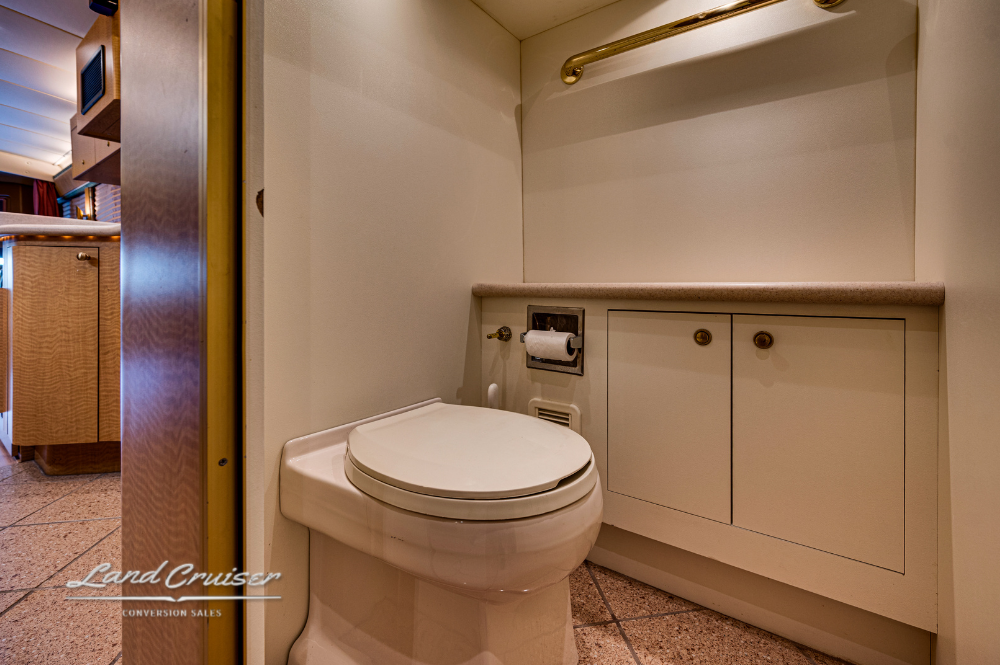 Private bathroom with toilet, sink, and storage in MCI motorhome