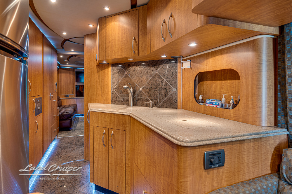 Curved galley kitchen counter with integrated sink, upper cabinets, and backsplash.
