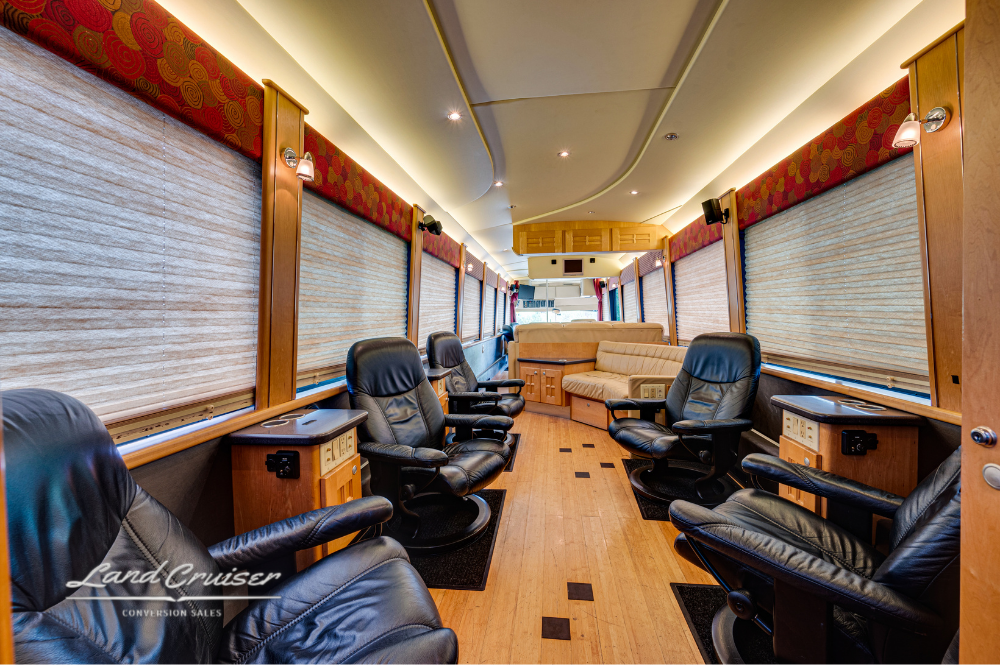 Salon view with six black leather captain’s chairs, wood flooring, and large shaded windows