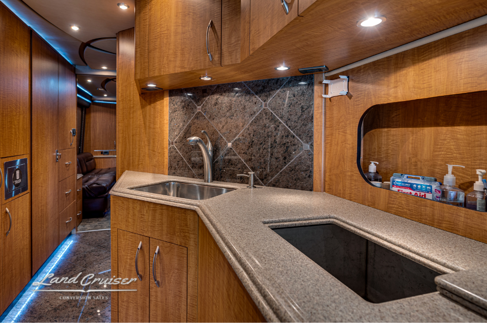 Corner kitchen layout with dual sink basins, tile backsplash, and integrated lighting.
