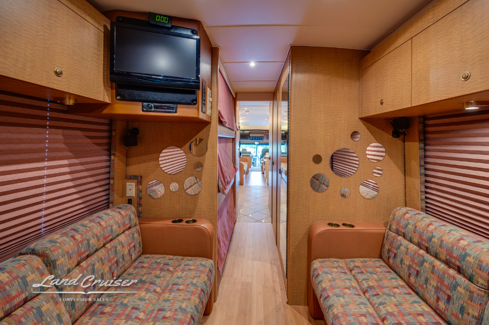 Rear lounge entertainment setup with TV and overhead storage in MCI motorhome