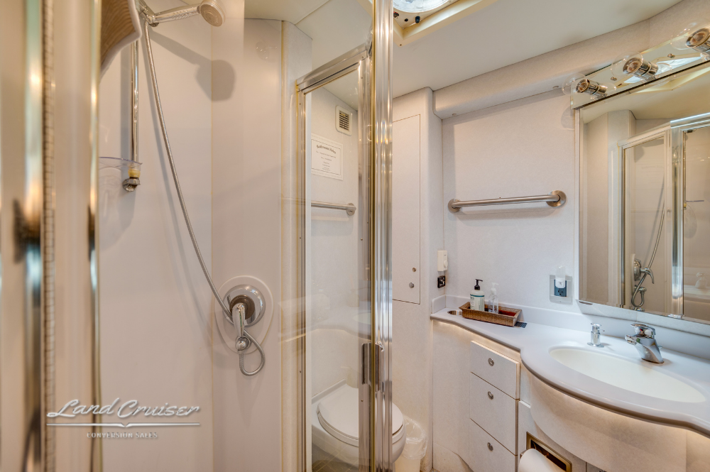 Glass-enclosed shower with adjustable sprayer and tiled interior in motorcoach bath