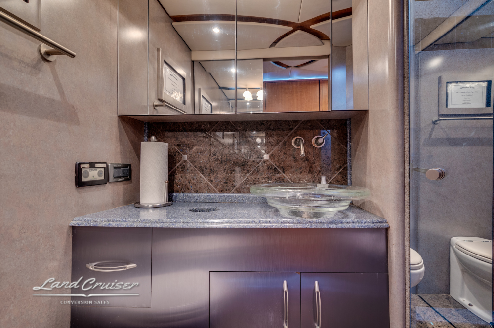 Luxury bathroom vanity with vessel sink, full-width mirror, and tile shower entry.