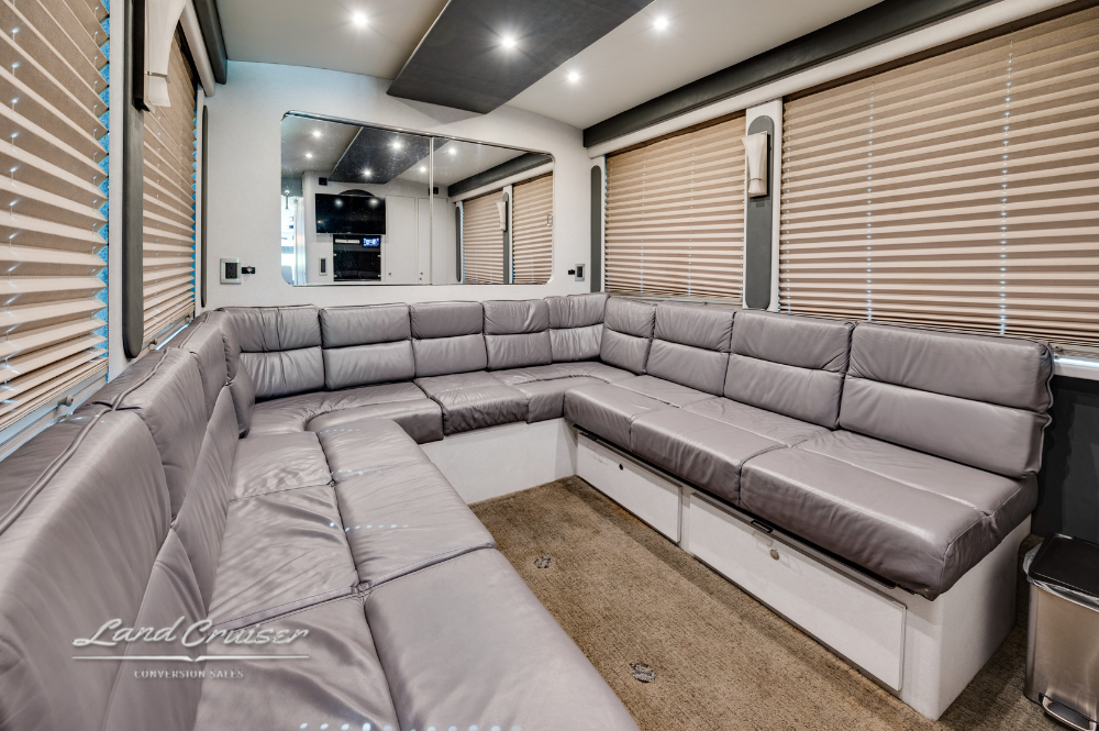 Custom executive coach interior with wraparound sleeper sofa and modern recessed lighting