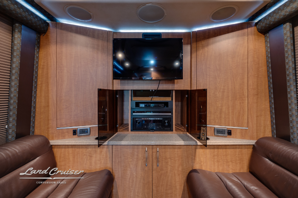 Rear entertainment center with built-in TV, stereo system, and leather captain chairs.