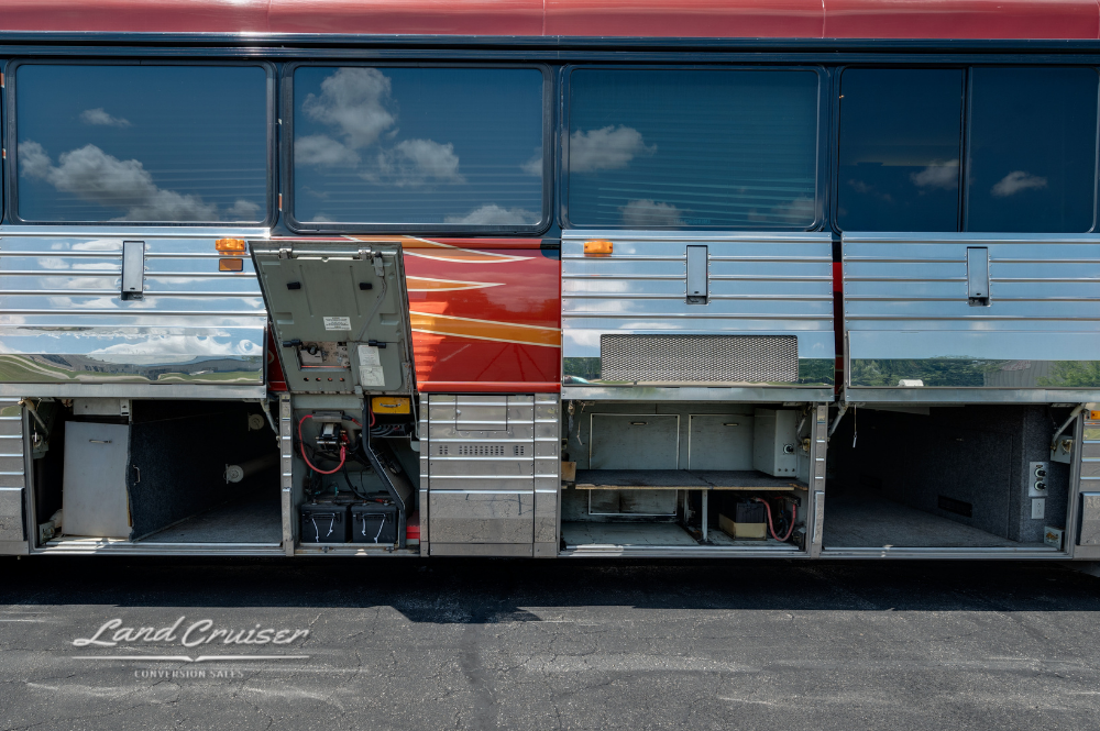 Passenger side storage bays open on 2001 MCI 102DL3 Executive Coach with stainless siding and red graphics