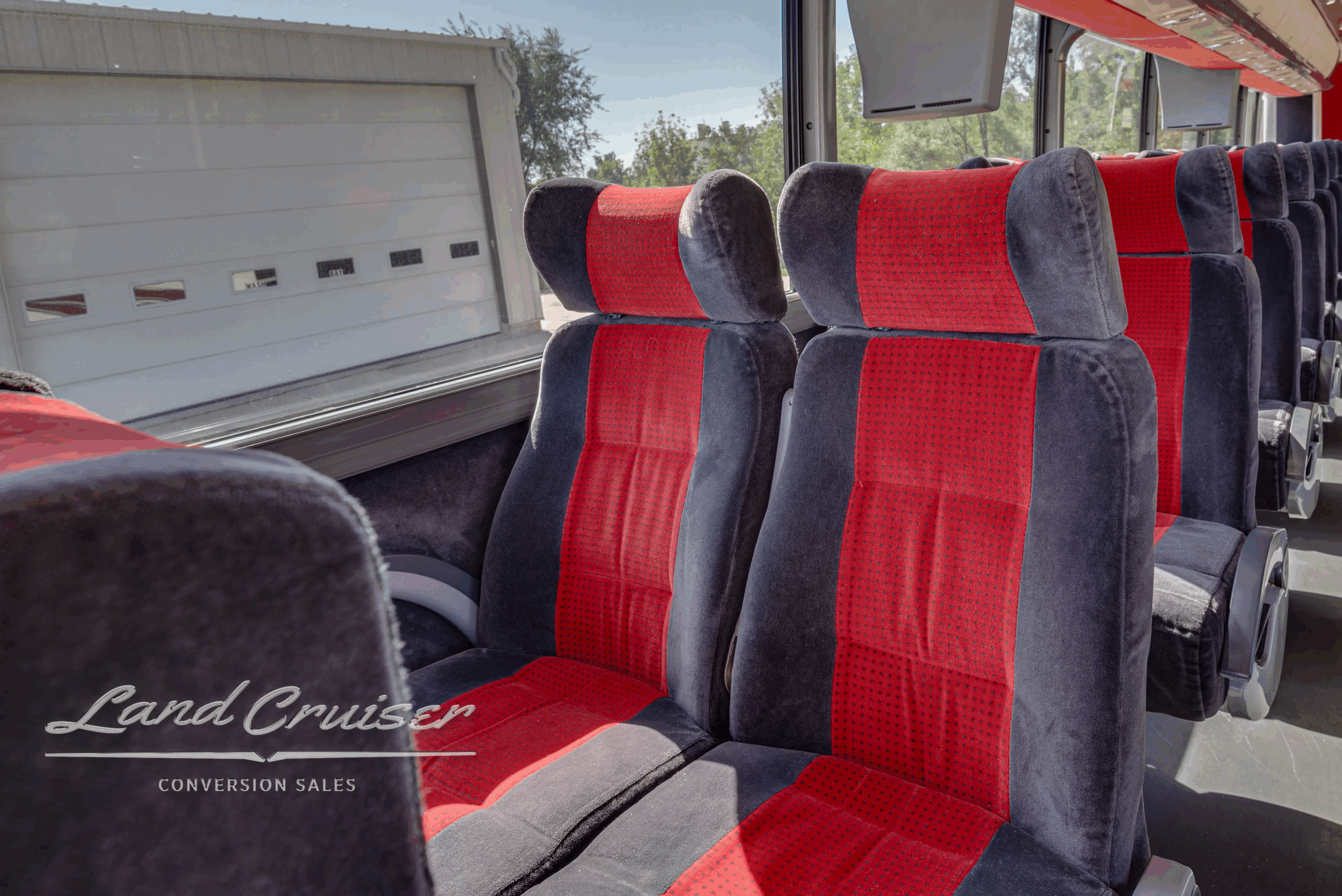 Passenger seats near window with red and gray upholstery.