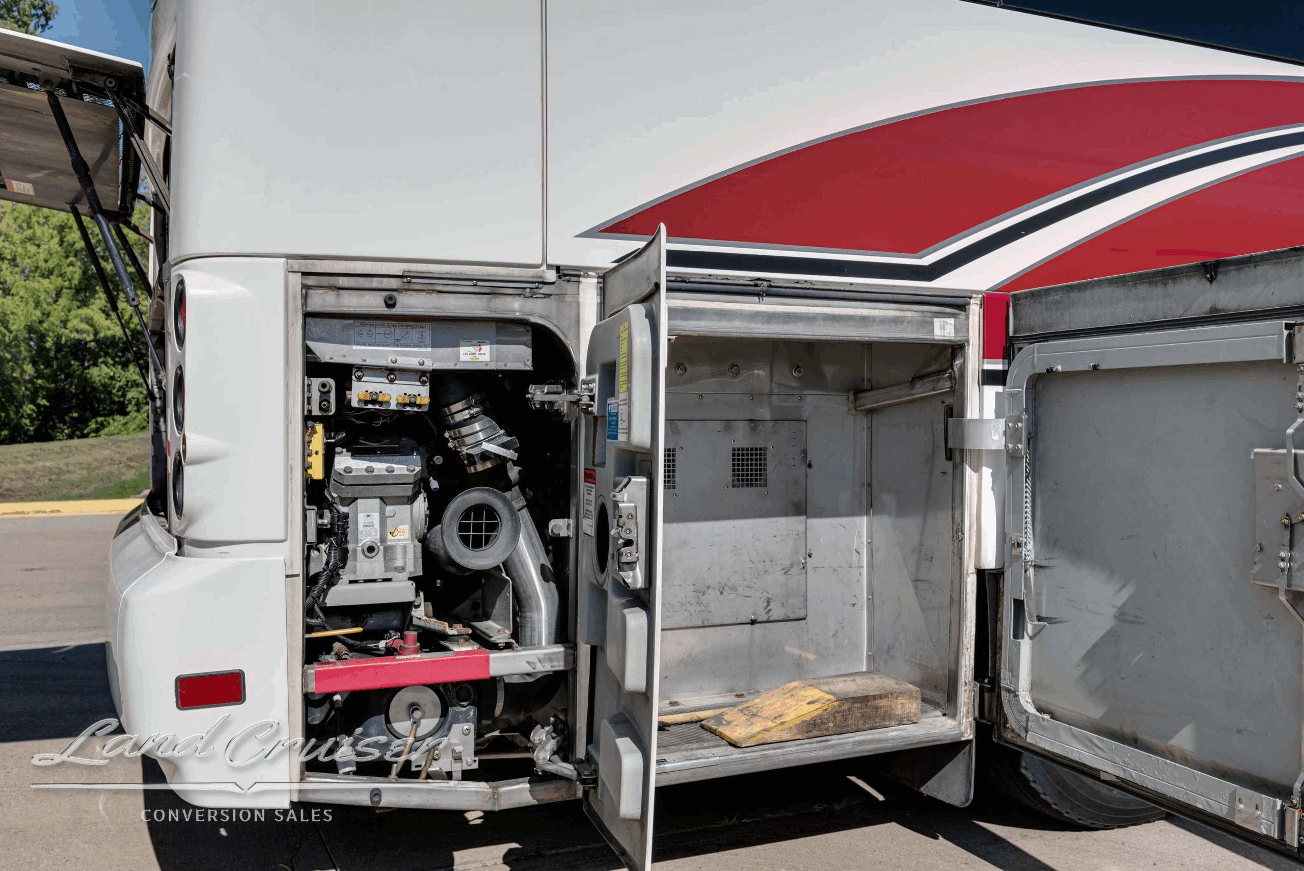 Engine service bay open with belts and pulleys visible.