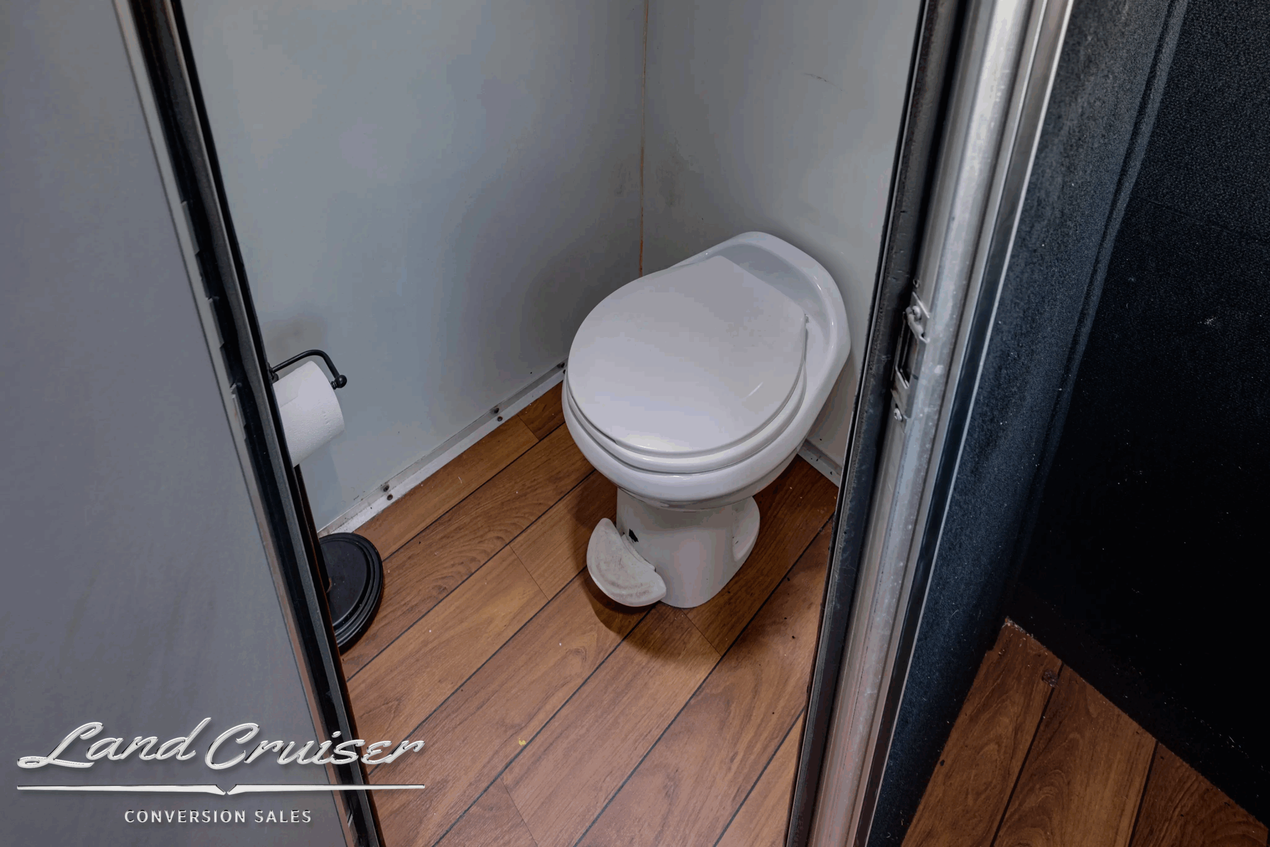 Onboard lavatory with toilet and wood-look flooring.
